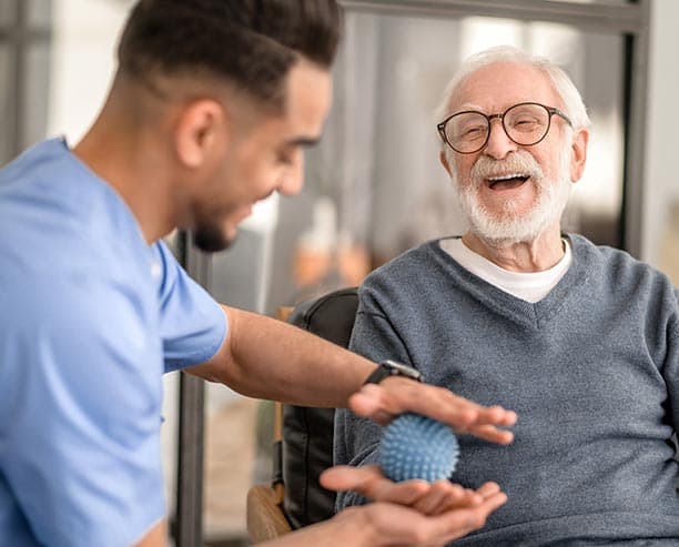 Male Nurse Conducting Hand Therapy On Elderly Man