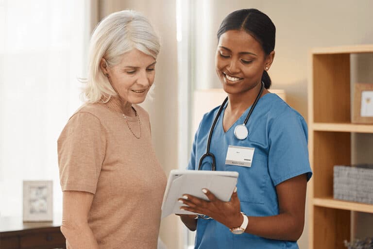 senior woman and nurse with a tablet talking to each other