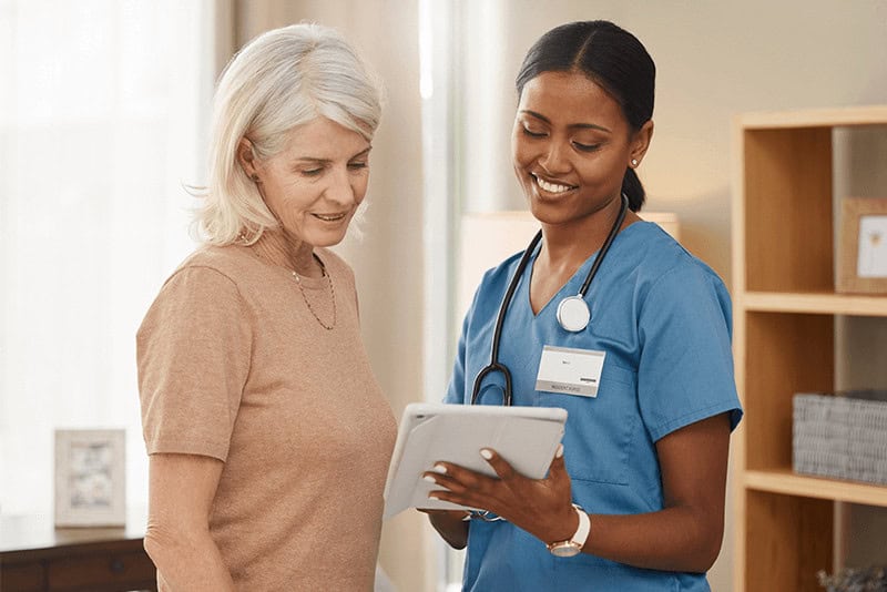 senior woman and nurse with a tablet talking to each other