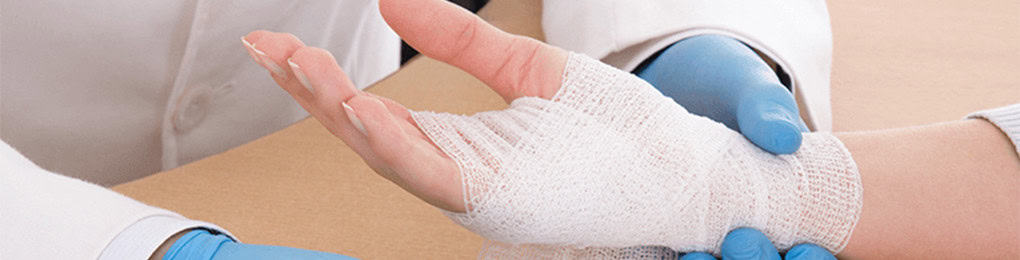 doctor in latex gloves wrapping bandage around a patient’s hand