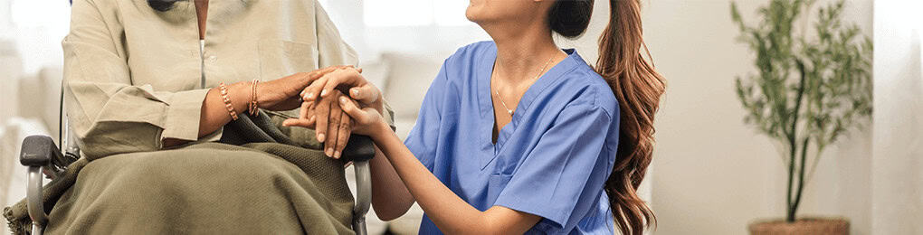 nurse talking to a woman in a wheelchair in a nursing home