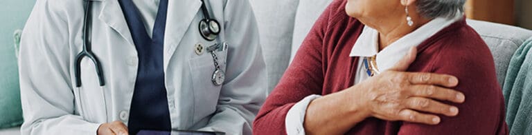 doctor with a tablet talking to a senior woman about her shoulder pain