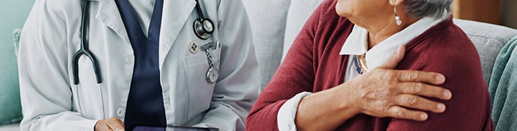 doctor with a tablet talking to a senior woman about her shoulder pain