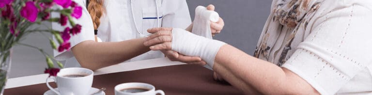 nurse performing home health care on senior woman by bandaging her wrist